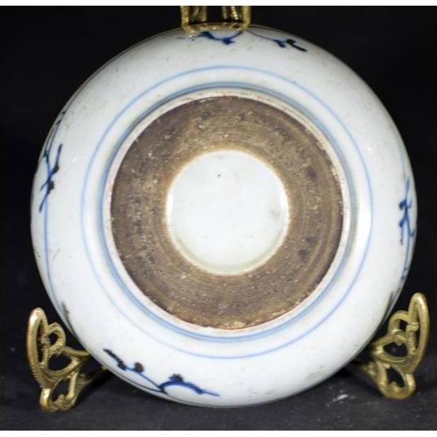 White and blue porcelain dish with rosette medallion and alternating panels, brown foot ring, on brass stand.