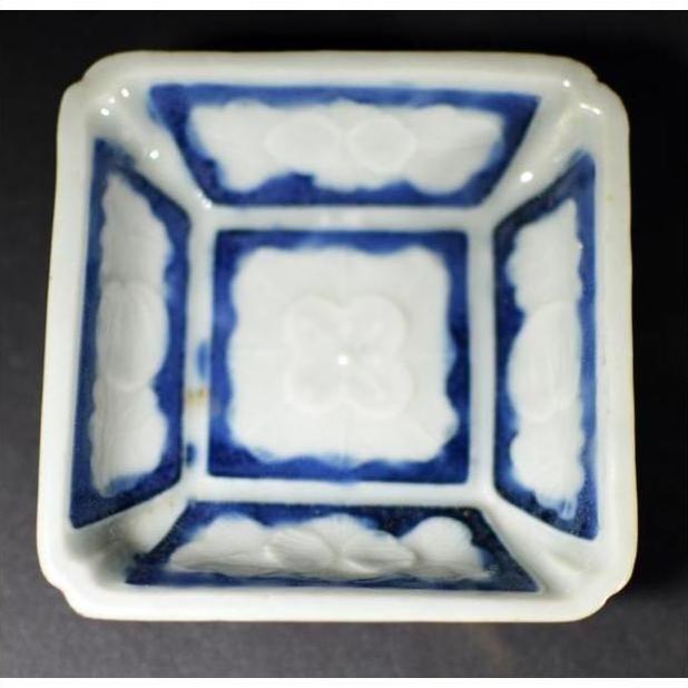 Blue-washed ceramic bowl with embossed blossom design on sides and center, close-up view.
