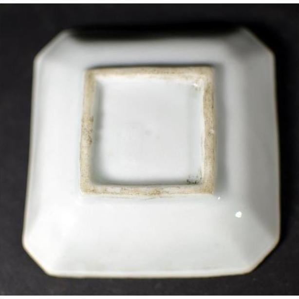 Close-up of the underside of an antique blue and white ceramic dish with chrysanthemum bloom, geometric frame, unglazed foot.