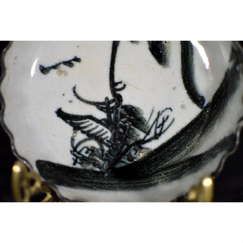 Close-up of white porcelain plate with bamboo branches and calligraphic brushwork in antique ink style.