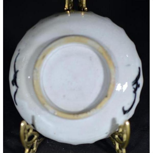 White porcelain plate with black ink-style bamboo design, displayed on an ornate gold stand, close-up view.