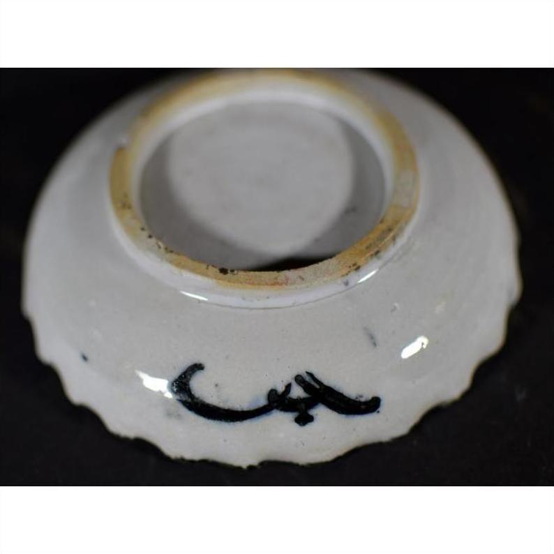 White porcelain plate with black bamboo and calligraphic brushwork, black base mark, close-up against dark background.