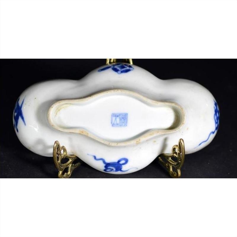 Blue ceramic cloud-form dish with river view and figural scene, shown upside down on brass stand revealing maker's mark.