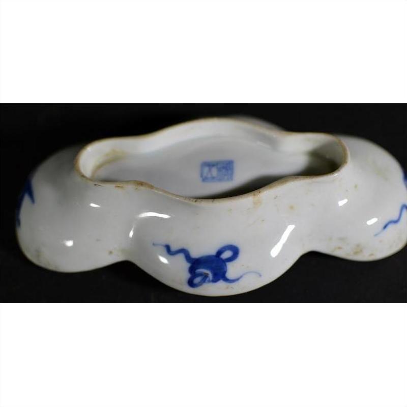 White ceramic cloud-form dish with wavy rim, blue floral and figural river scene, marked base, close-up.
