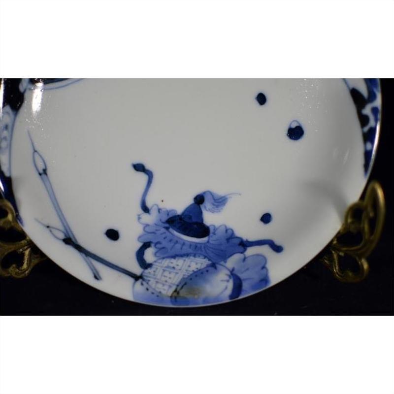 Close-up of antique porcelain plate with hand-painted oxen and lattice border, displayed on gold-colored stand.