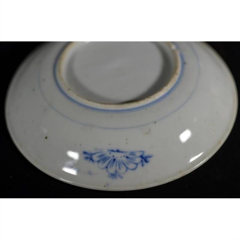 Close-up of the underside of a white porcelain plate with a small blue floral design near the base.