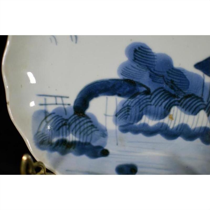 White porcelain plate with hand-painted blue clouded mountain landscape, close-up.
