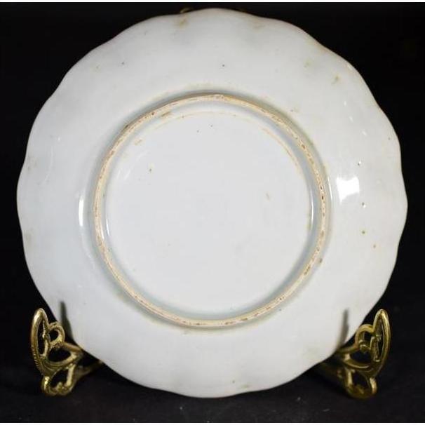 White porcelain plate with hand painted Chinese clouded mountain landscape on ornate gold stand, black background.