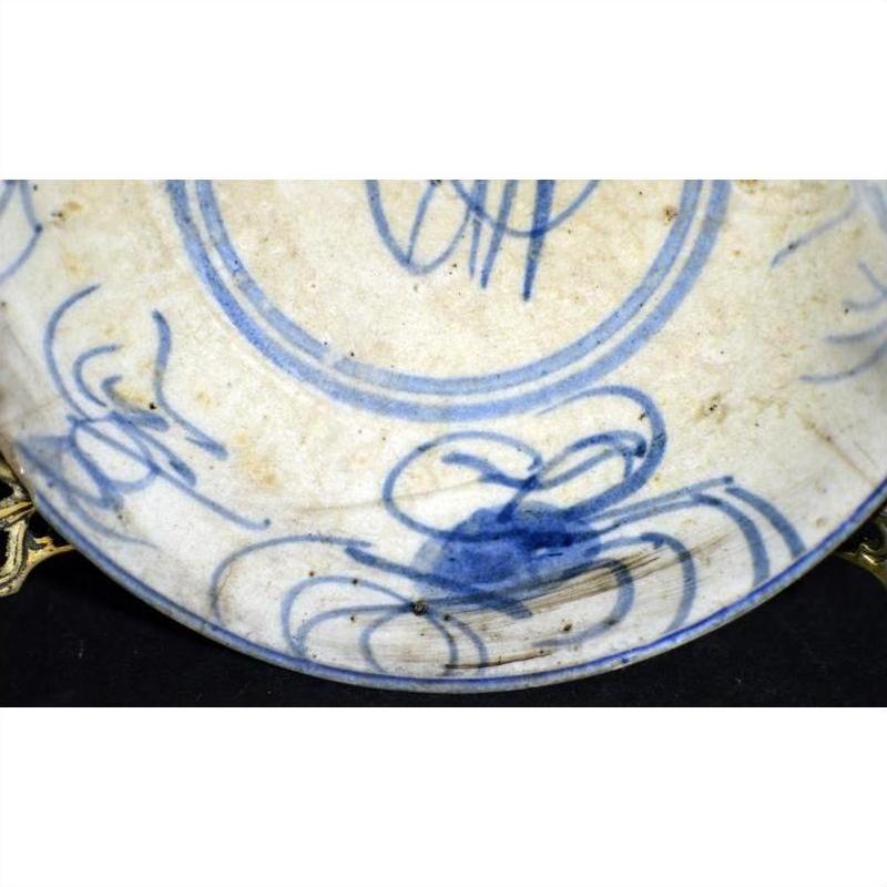 Close-up of off-white porcelain plate with hand-painted blue abstract patterns and butterfly design, antique Chinese style.
