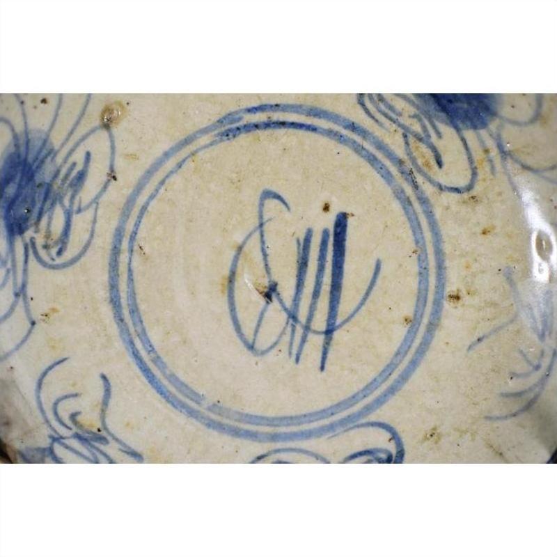 Blue and white porcelain plate with hand-painted butterfly and abstract floral design, close-up.