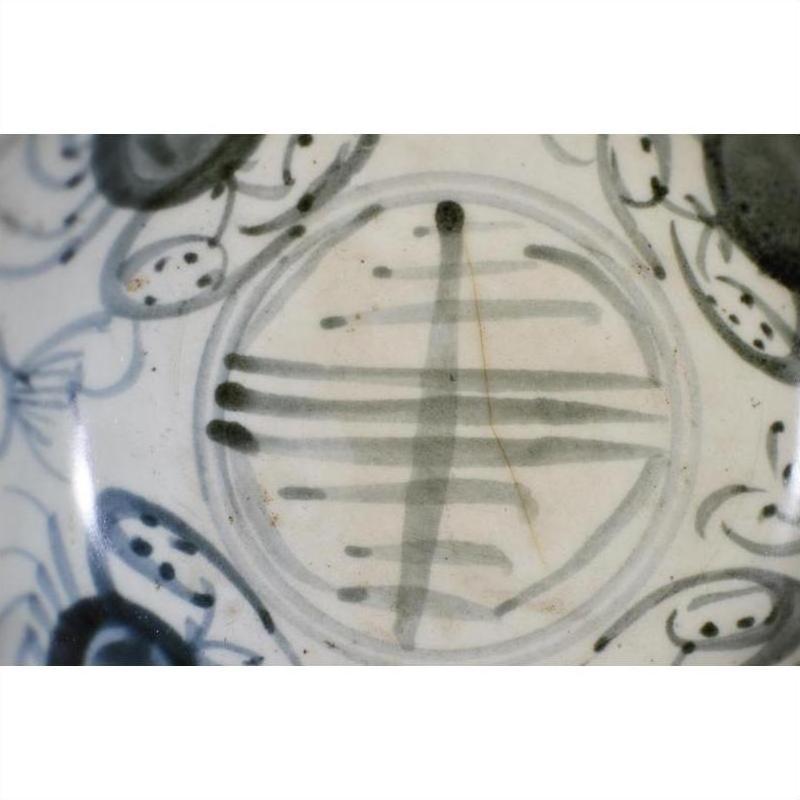 Close-up of an antique painted porcelain plate with abstract radial lines and a floral ring design.