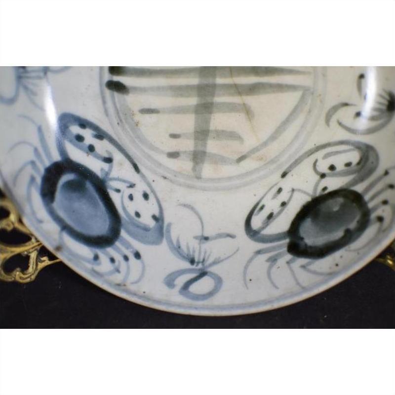 Close-up of white antique porcelain plate with painted abstract radial lines and floral ring near the rim.