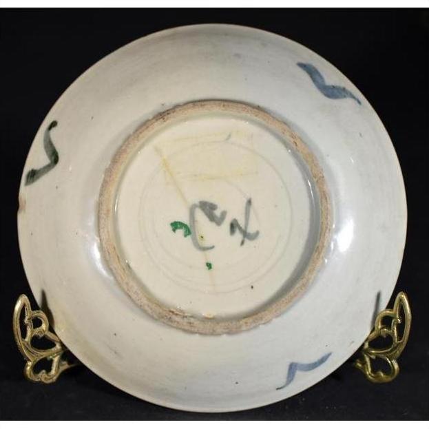 Close-up of the underside of an antique painted porcelain plate with abstract radial lines and a floral ring on black.