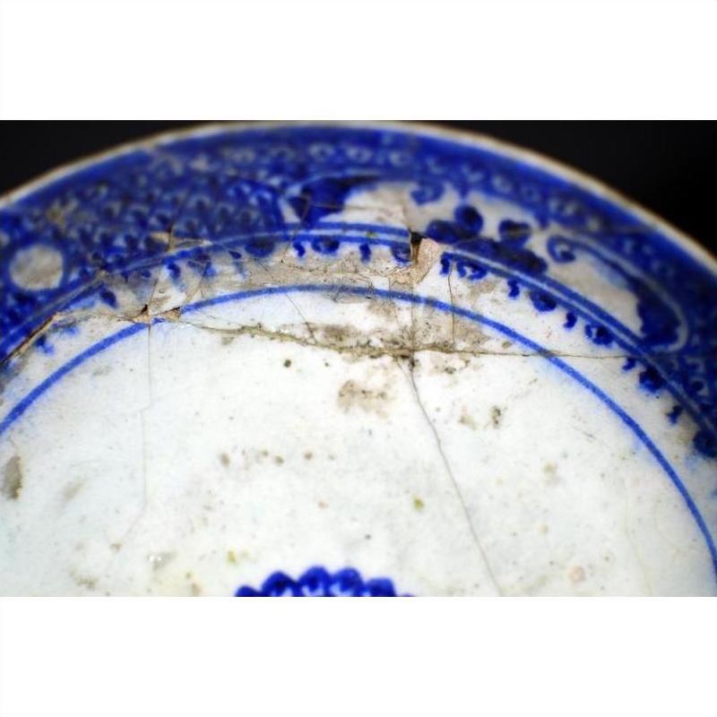 Close-up of blue ceramic Antique Radial Medallion Plate with cracks, dirt, and detailed Inner Sunburst pattern.