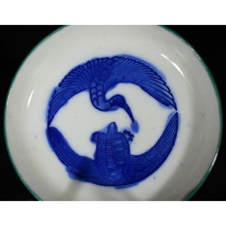 White ceramic plate with antique crane and turtle design, both animals facing each other, close-up view.