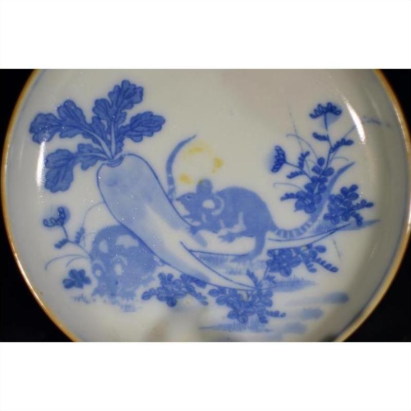 Blue and white ceramic dish with painted garden scene, featuring two mice, a radish, and floral accents.