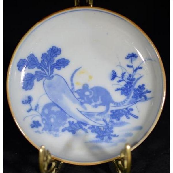 Antique painted ceramic dish with mouse duo and radish garden scene, displayed on a brass stand.