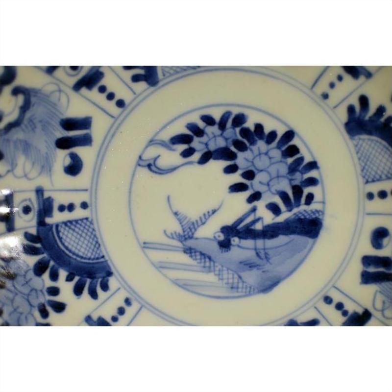 Blue and white porcelain plate with hand painted bird, floral, and geometric motifs, antique Chinese design, close-up.