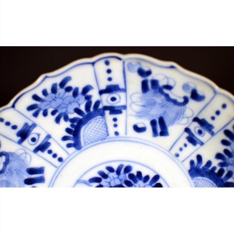 Blue and white porcelain plate with intricate hand painted floral and geometric patterns, antique style, close-up.