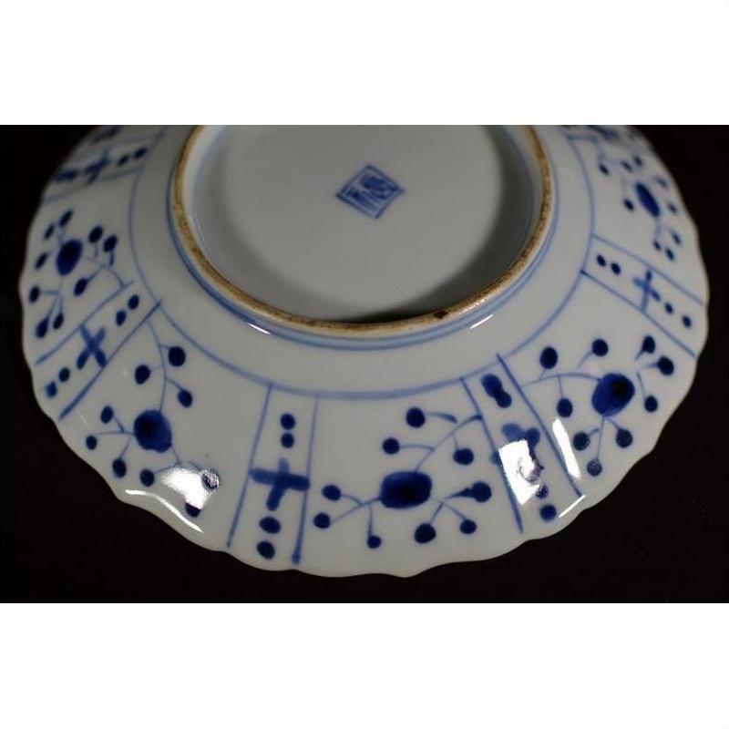Blue and white porcelain plate underside with hand painted patterns and a central square hallmark.
