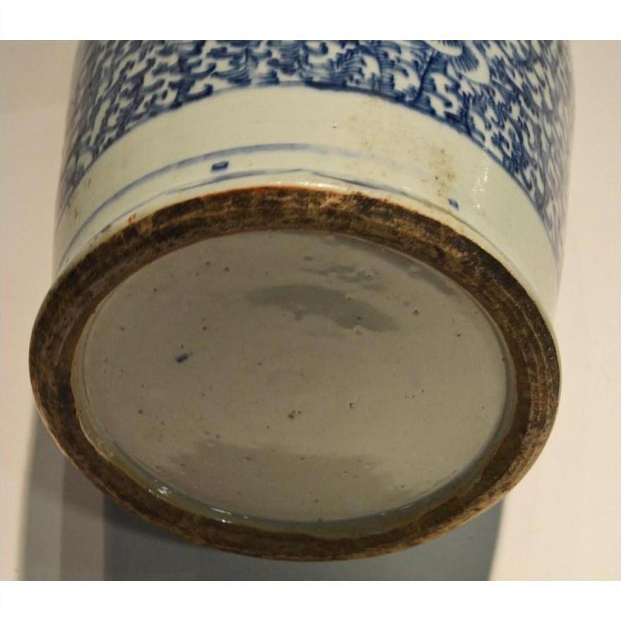 Close-up of blue and white ceramic vase base, hand painted, with unglazed rim and slight staining.