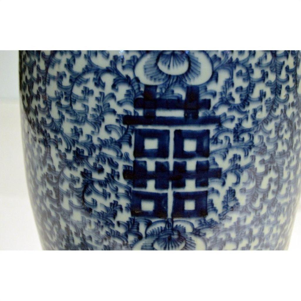Close-up of blue and white ceramic Chinese vases with hand painted floral patterns and bold character symbols, weathered finish.