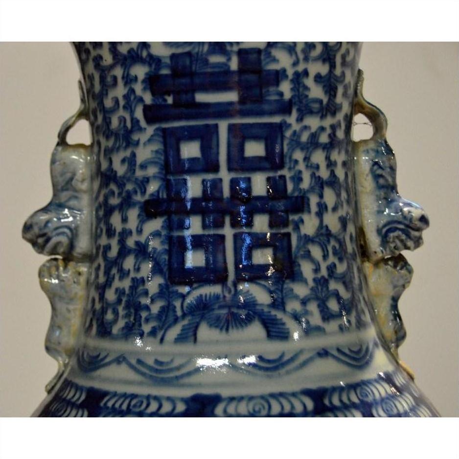 Close-up of blue and white ceramic Chinese vase with hand painted patterns and Chinese characters, weathered finish.