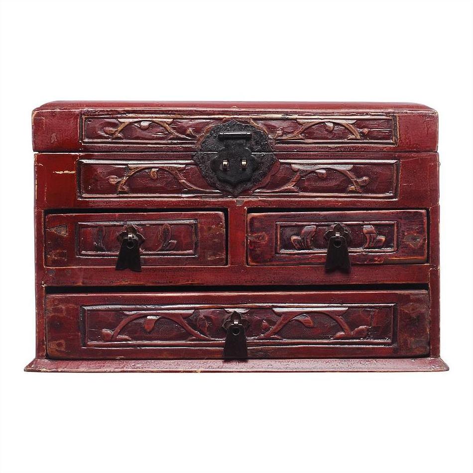 Dark red lacquered wood Chinese jewelry box with carved floral designs, multiple drawers, black metal handles, close-up.