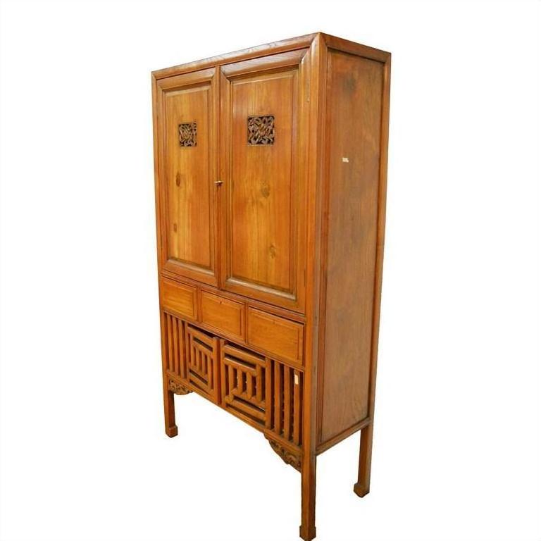 Brown wood Chinese kitchen cabinet with hand-carved framework, two doors, and three drawers, front view.