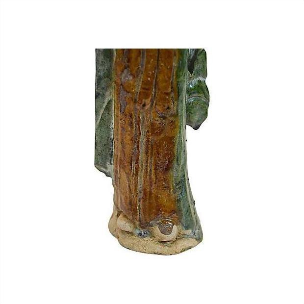 Close-up of brown and green glazed terracotta court figure statue base and feet.