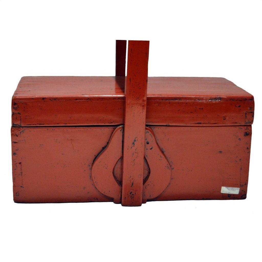 Close-up of antique Chinese red lacquer wood box with tall handle, latch, and worn aged red paint.