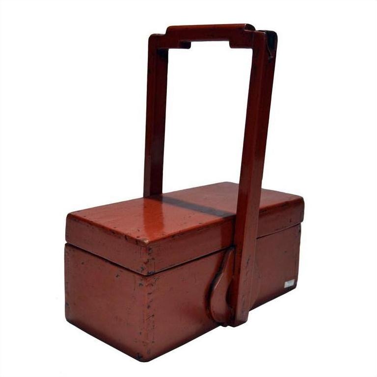 Close-up of antique Chinese red lacquer wood box with tall handle and two compartments, decorative display piece.