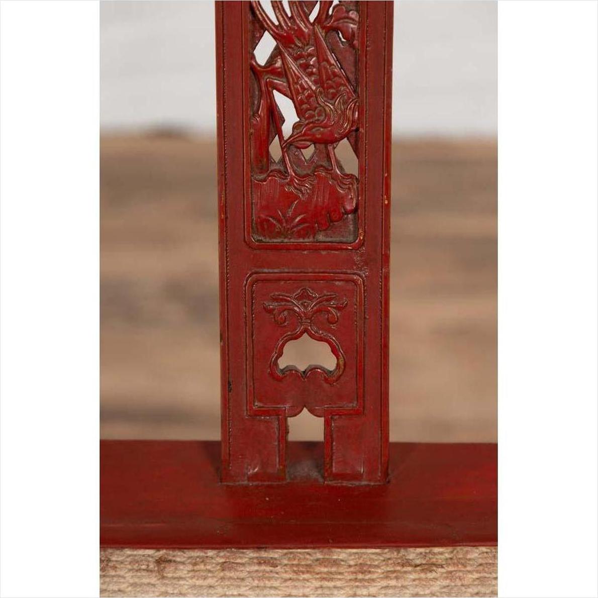 Close-up of red lacquered wood folding chair with footrest and fabric upholstery, antique Chinese style.