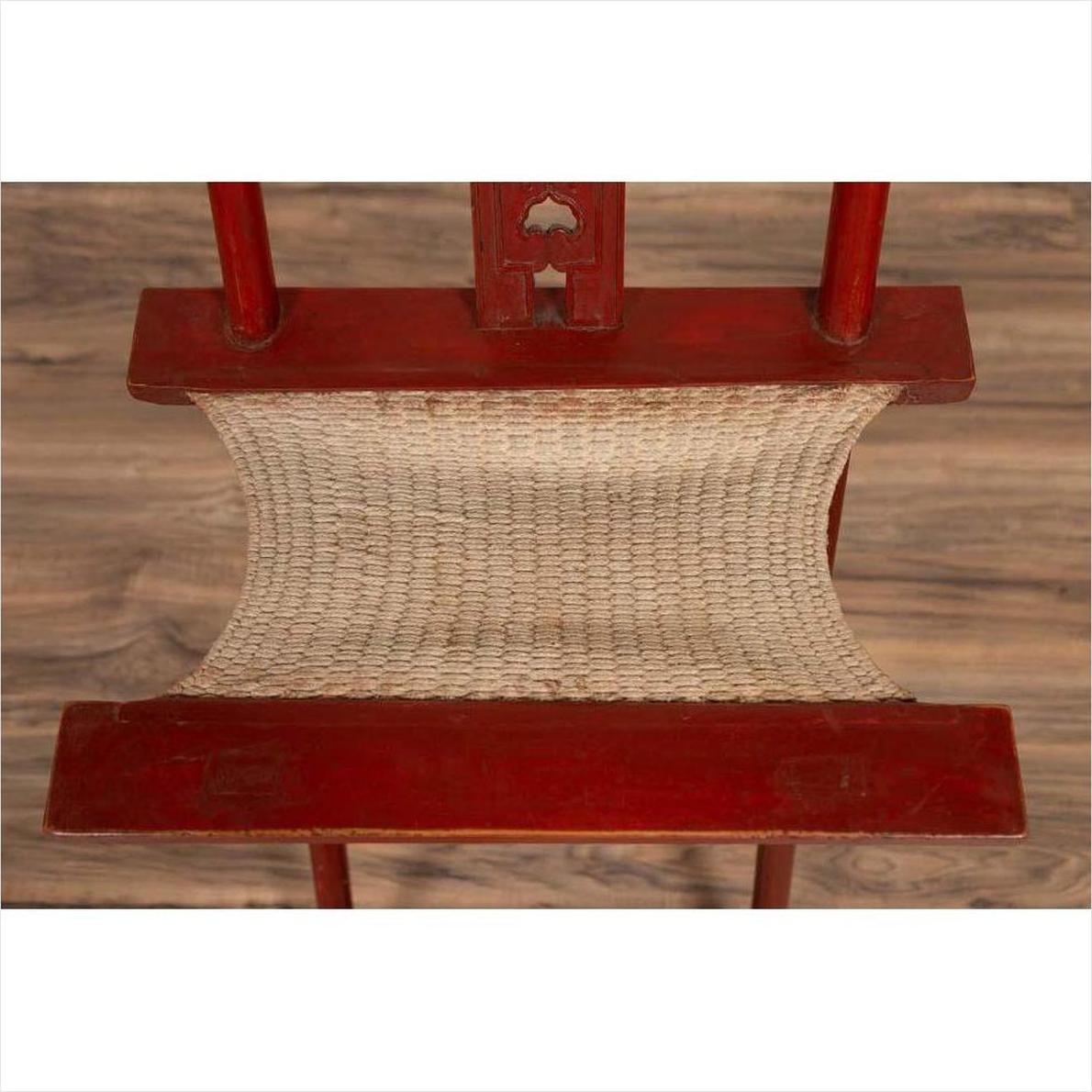 Red lacquered wood folding chair with footrest and fabric, on wood floor.