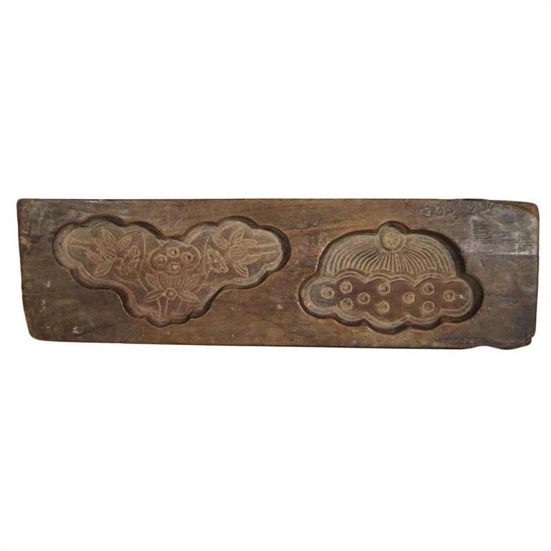 Brown wood antique Chinese rice mold with two carved designs for traditional pastries, close-up on plain background.