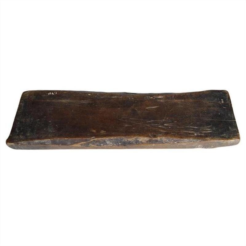 Close-up of a dark wooden antique Chinese rice mold with visible wear and scratches on a white background.