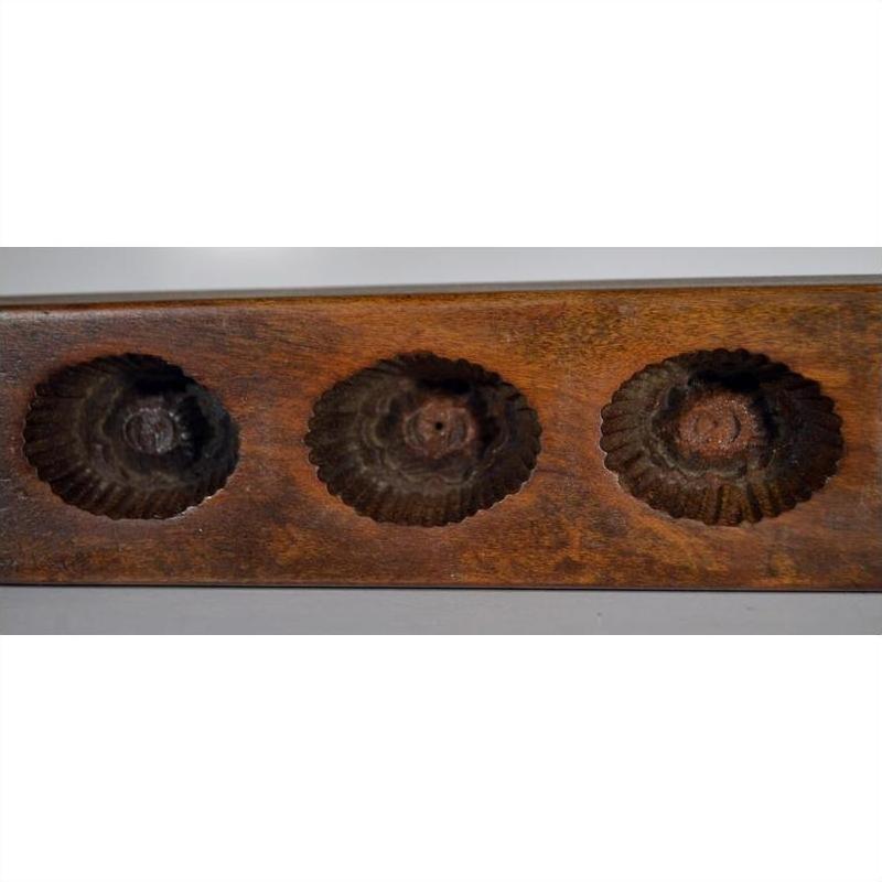 Close-up of antique Chinese rice mold with three scalloped round indentations, ceramic material visible.