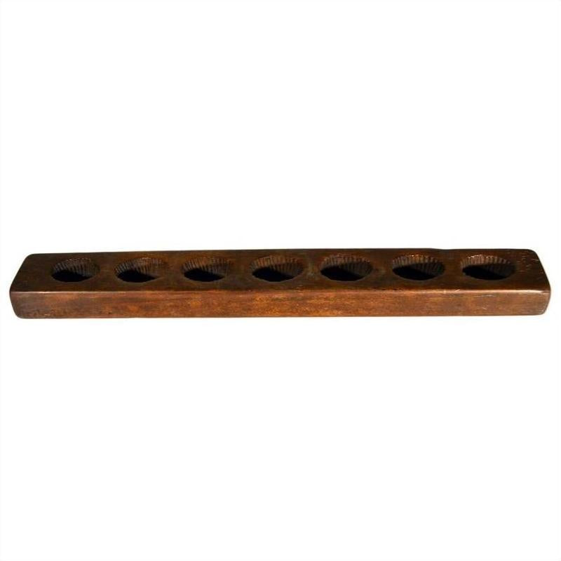 Brown wooden rectangular Chinese rice mold with eight evenly spaced round holes on top, close-up view.