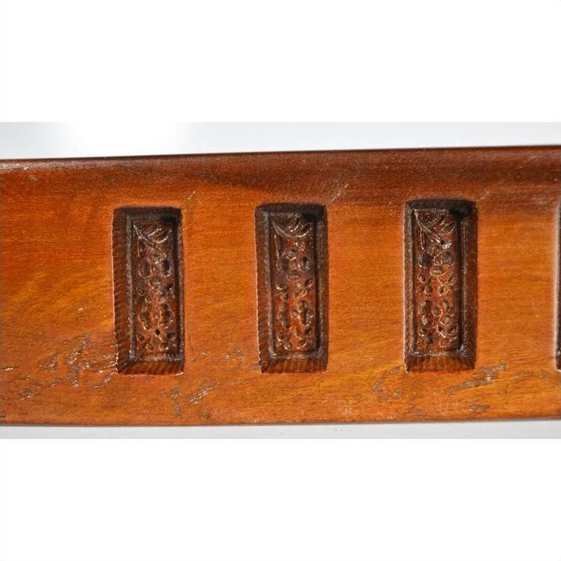 Close-up of three antique wooden Chinese rice mold panels arranged in a row on a wooden surface.