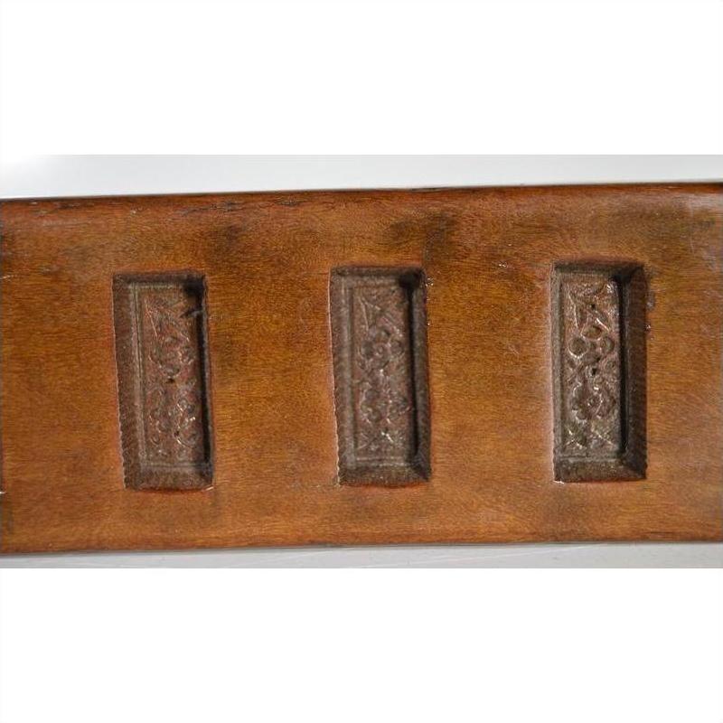 Close-up of antique wooden Chinese rice mold with three ornate rectangular carved panels in a row.