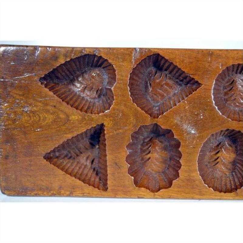 Brown wooden antique Chinese rice mold with geometric eight-shape design, close-up on plain surface.