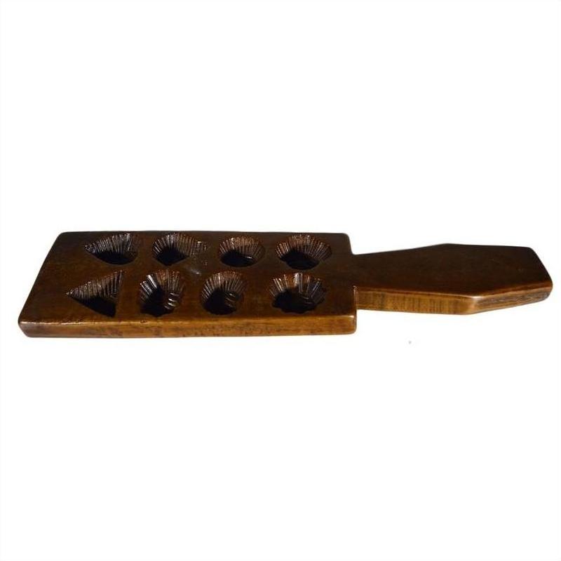 Brown wooden Chinese rice mold with eight geometric cavities and handle, close-up on plain background.