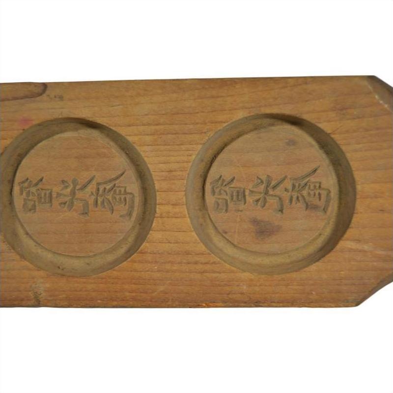 Light wood antique Chinese rice mold with three round character stamps, close-up.