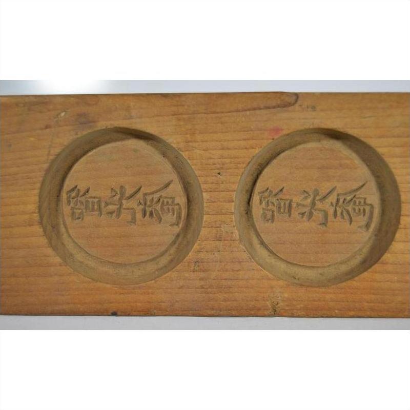 Close-up of light wood antique Chinese rice mold with three round character stamps.