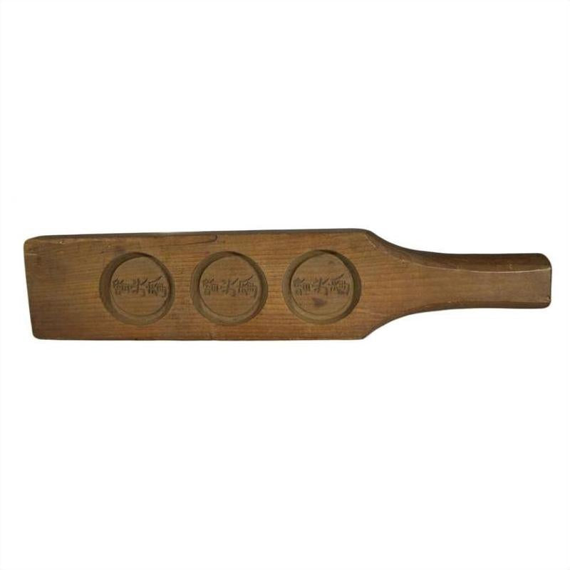 Light wood antique Chinese rice mold with three round character stamps, close-up, used for shaping food.