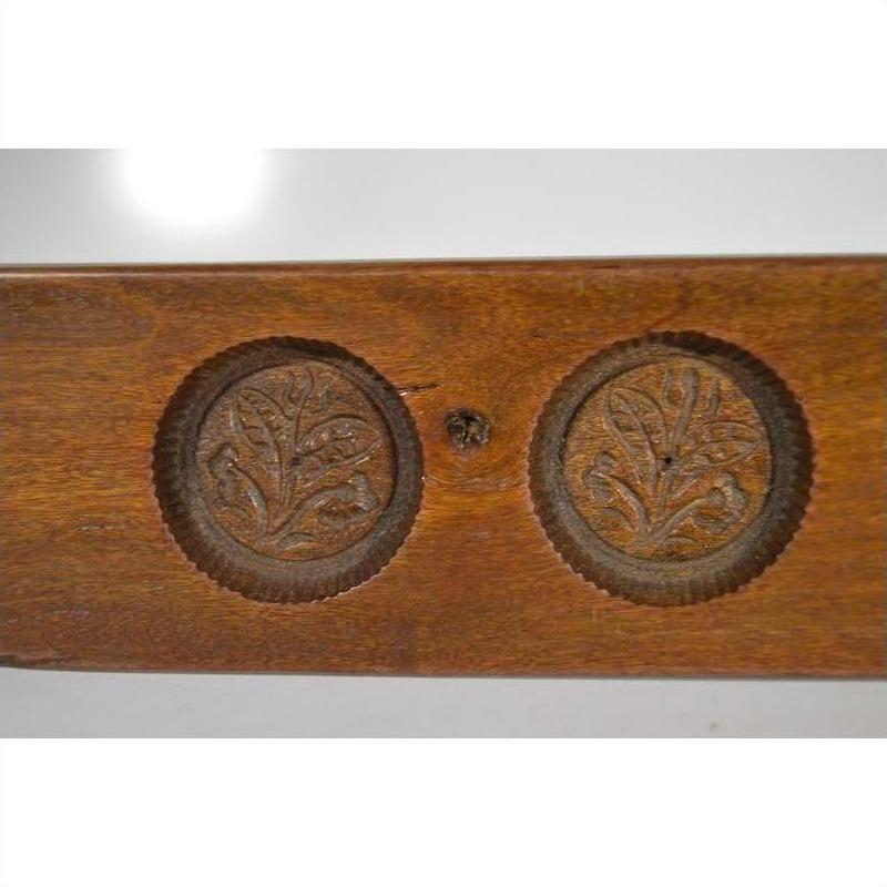 Close-up of brown antique wooden Chinese rice mold with five leaf bud impressions and a symmetrical floral motif carving.