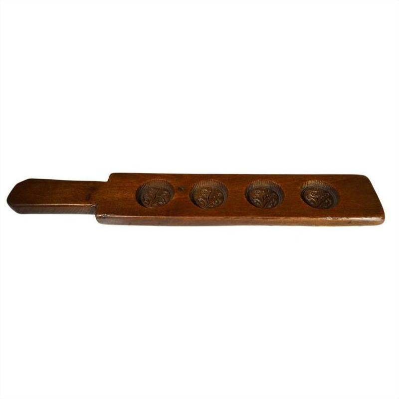 Brown wooden antique Chinese rice mold with handle and five leaf bud impressions, displayed on a neutral background.