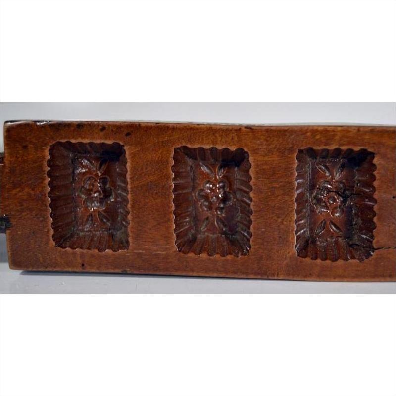 Brown antique Chinese wooden rice mold with seven rectangular motifs, close-up on a flat surface.