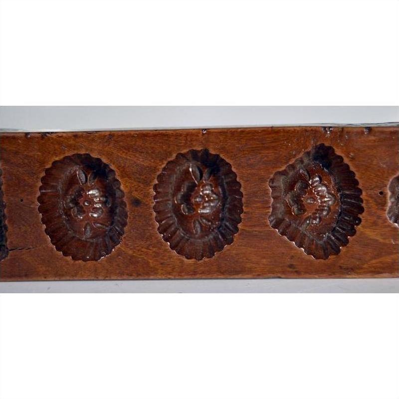 Close-up of antique Chinese rice mold, brown wood, with seven rectangular mixed-motif cavities.