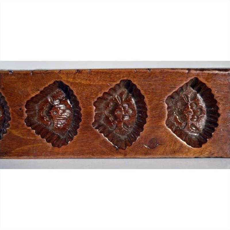 Brown wood antique Chinese rice mold with seven rectangular mixed motif cavities, close-up on plain background.